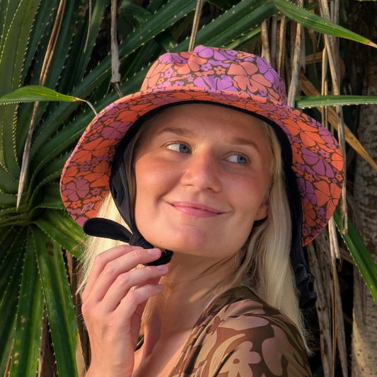 Woman wearing a colorful floral surf bucket hat among plants